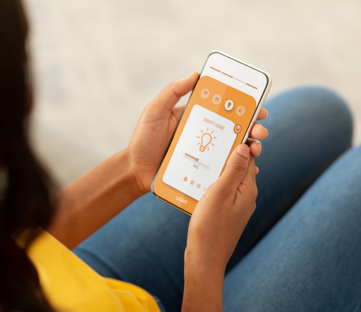 Main tenant un smartphone connecté pour contrôler l’éclairage domotique, à Pau